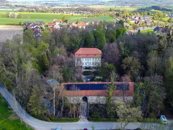 Luftaufnahme von Schloss Reelkirchen mit rotem Dach, umgeben von Bäumen in ländlicher Umgebung.