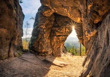 Kleinstein Cave Rock arch of the Kleinstein Cave with a view of a sunny forest, the sun shining through the opening, warm colors and a calm, natural atmosphere.