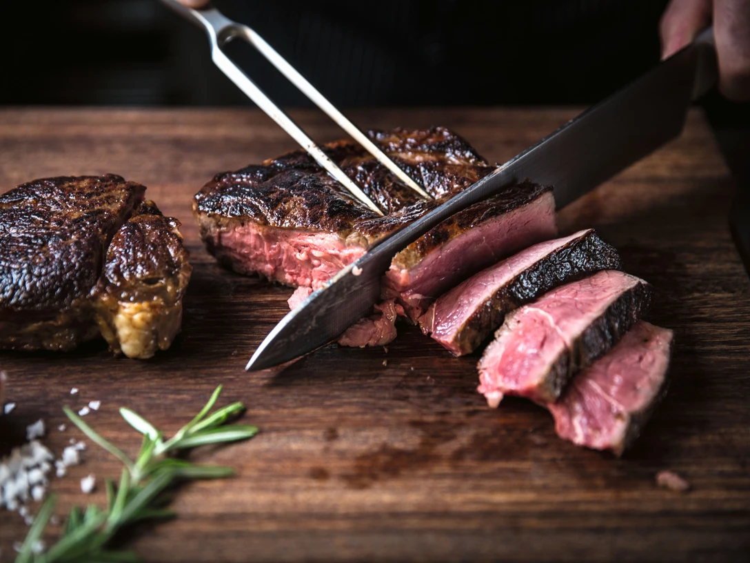 Dry aged beef im STEAKTRAIN - Gastronomie in Leipzig Auf einem Schneidebrett aus Holz wird das dry aged beef aus dem Restaurant STEAKTRAIN des Seaside Park Hotel aufgeschnitten