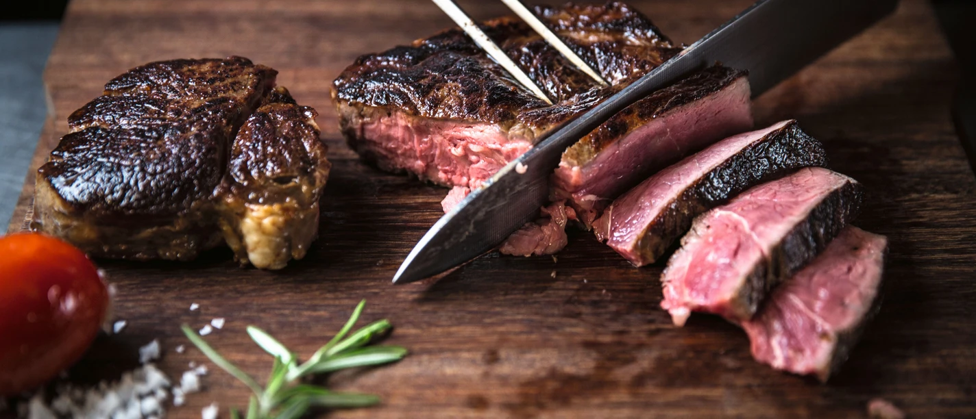 Dry aged beef im STEAKTRAIN - Gastronomie in Leipzig Auf einem Schneidebrett aus Holz wird das dry aged beef aus dem Restaurant STEAKTRAIN des Seaside Park Hotel aufgeschnitten