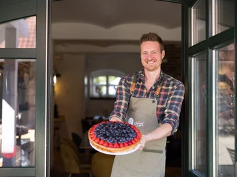 Das Mauerwerk Auf dem Bild ist der Inhaber des Mauerwerks zu sehen, der stolz einen seiner prachtvollen Kuchen präsentiert.