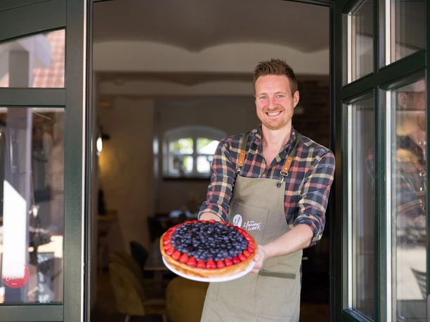 Das Mauerwerk Auf dem Bild ist der Inhaber des Mauerwerks zu sehen, der stolz einen seiner prachtvollen Kuchen präsentiert.