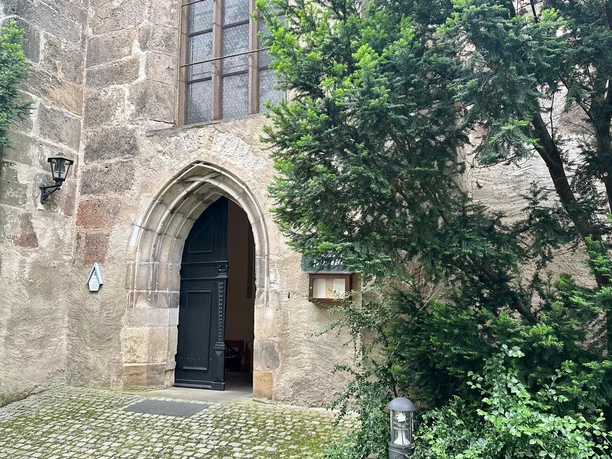 Entrance to the monastery church of St. Heinrich in Pirna with Gothic arch and surrounding nature.