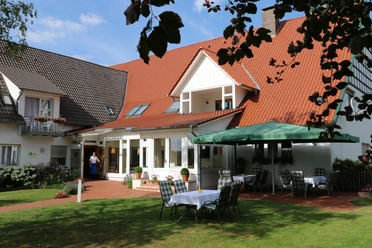 Landhaus Blankenstein Landhaus Blankenstein mit roten Dachziegeln und Garten, Tische unter einem grünen Sonnenschirm.