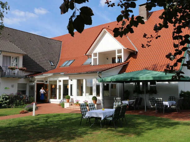 Landhaus Blankenstein Landhaus Blankenstein mit roten Dachziegeln und Garten, Tische unter einem grünen Sonnenschirm.