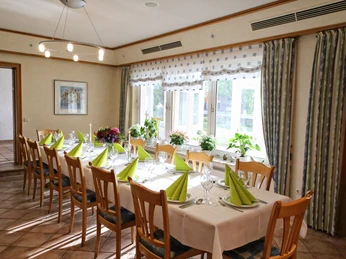 Landhaus Blankenstein Ein elegant gedeckter Speisesaal mit langen Holztischen, grün gefalteten Servietten und Kerzenlicht.