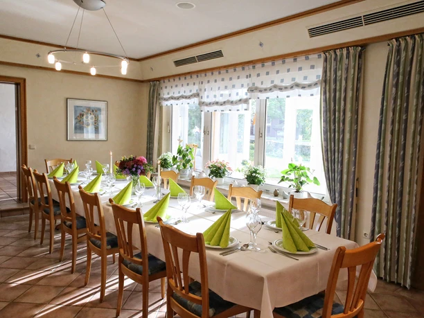 Landhaus Blankenstein Ein elegant gedeckter Speisesaal mit langen Holztischen, grün gefalteten Servietten und Kerzenlicht.