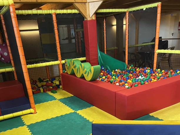 Western Joe.jpeg Bunter Indoor-Spielbereich mit Bällebad, Rutsche und weichen Matten zum Toben und Klettern.