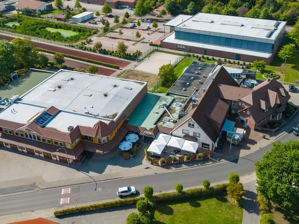 Lüns von oben.jpg Luftaufnahme des Restaurants Lüns mit rotem Ziegeldach, Außenterrasse und umliegenden Gebäuden