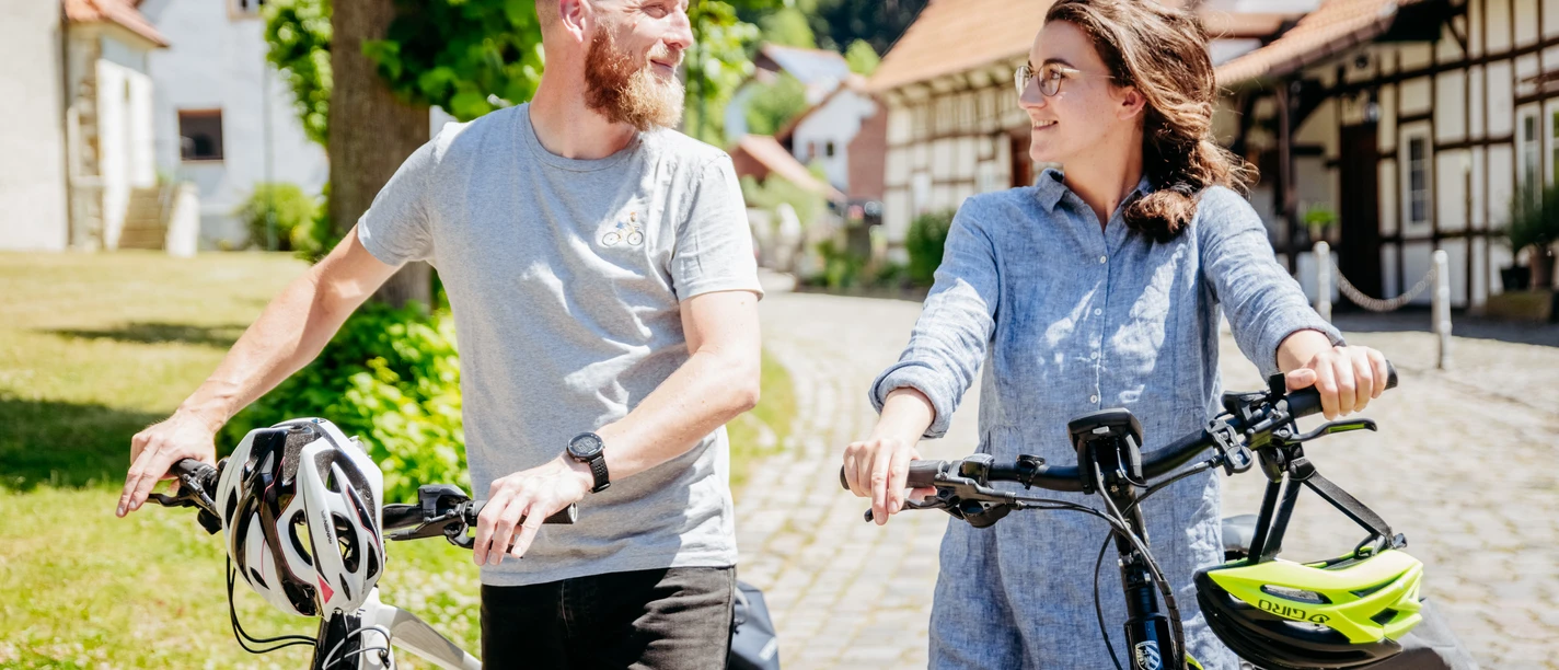 Bissendorf-Holte Two people push bicycles through a sunny village with half-timbered houses.
