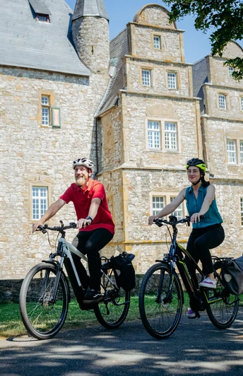 Die Schelenburg bei Bissendorf Zwei Radfahrer vor einem historischen steinernen Herrenhaus bei sonnigem Wetter.Two cyclists in front of a historic stone manor house in sunny weather.To cyklister foran en historisk herregård af sten i solskinsvejr.Twee fietsers voor een historisch stenen landhuis bij zonnig weer.