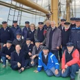 Shanty Chor Dümmer See Eine Gruppe freundlicher Männer im einheitlichen Marineoutfit steht auf einem historischen Segelschiff.