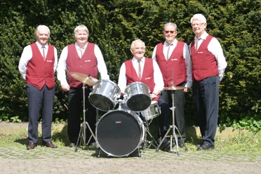 Die flotten Oldies Die flotten Oldies.jpg Fünf ältere Herren in roten Westen stehen lächelnd neben einem Schlagzeug, vor grünen Büschen.