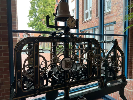 Uhrwerk Antikes Uhrwerk von J.F. Weule aus Bockenem, eingefasst in einem Fensterrahmen mit Blick ins Freie.