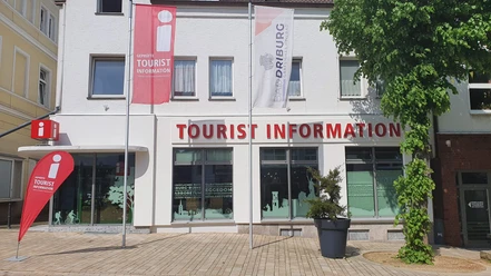 Tourist-Information in Bad Driburg mit klarer Beschilderung, Fahnen und einem bepflanzten Umfeld.
