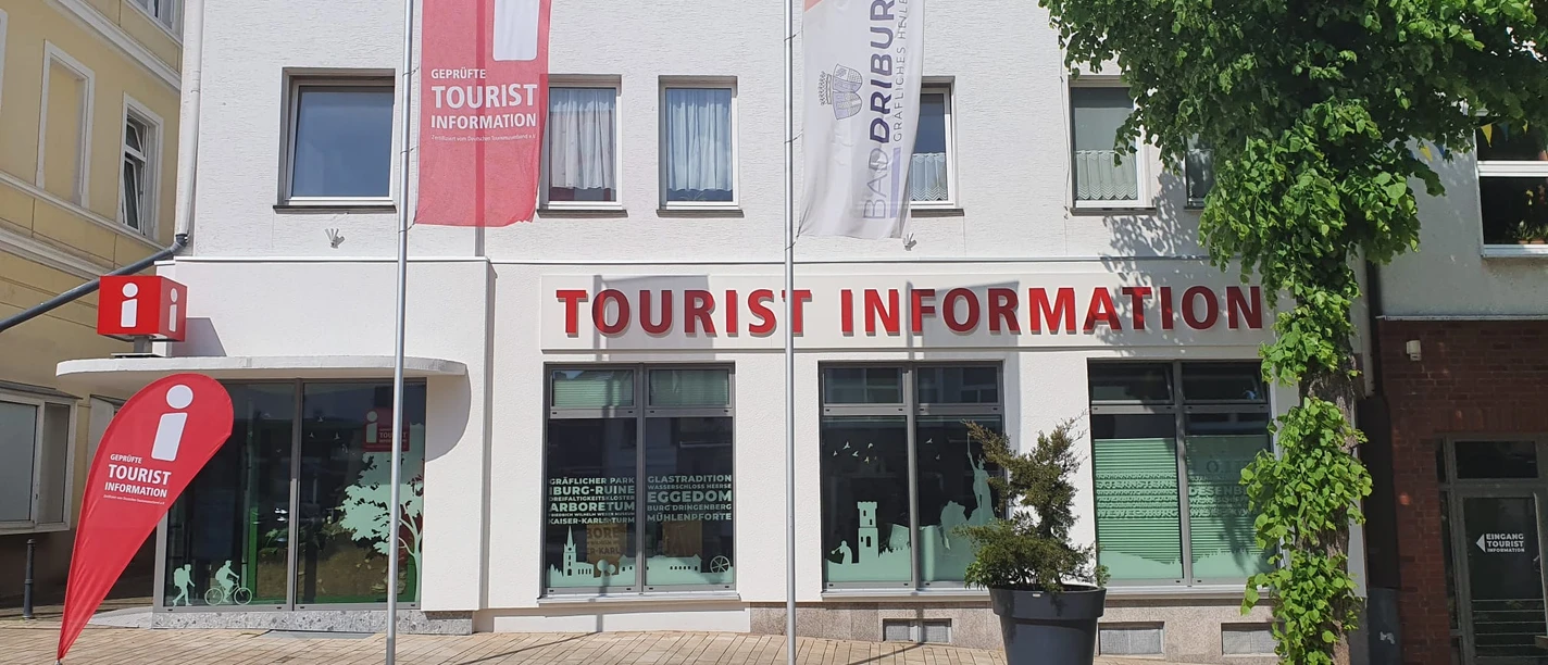 Tourist-Information in Bad Driburg mit klarer Beschilderung, Fahnen und einem bepflanzten Umfeld.