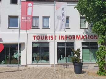 Tourist-Information in Bad Driburg mit klarer Beschilderung, Fahnen und einem bepflanzten Umfeld.