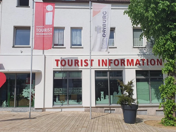 Tourist-Information in Bad Driburg mit klarer Beschilderung, Fahnen und einem bepflanzten Umfeld.