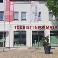 Bad Driburg_Tourist Information_Ausenansicht Tourist-Information in Bad Driburg mit klarer Beschilderung, Fahnen und einem bepflanzten Umfeld.