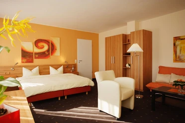 Senne Hotel20071019_0055.jpg Modern eingerichtetes Hotelzimmer mit Doppelbett, Sessel, Sofa, Kleiderschrank und warmen Farbtönen.