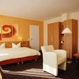 Senne Hotel20071019_0055.jpg Modern eingerichtetes Hotelzimmer mit Doppelbett, Sessel, Sofa, Kleiderschrank und warmen Farbtönen.