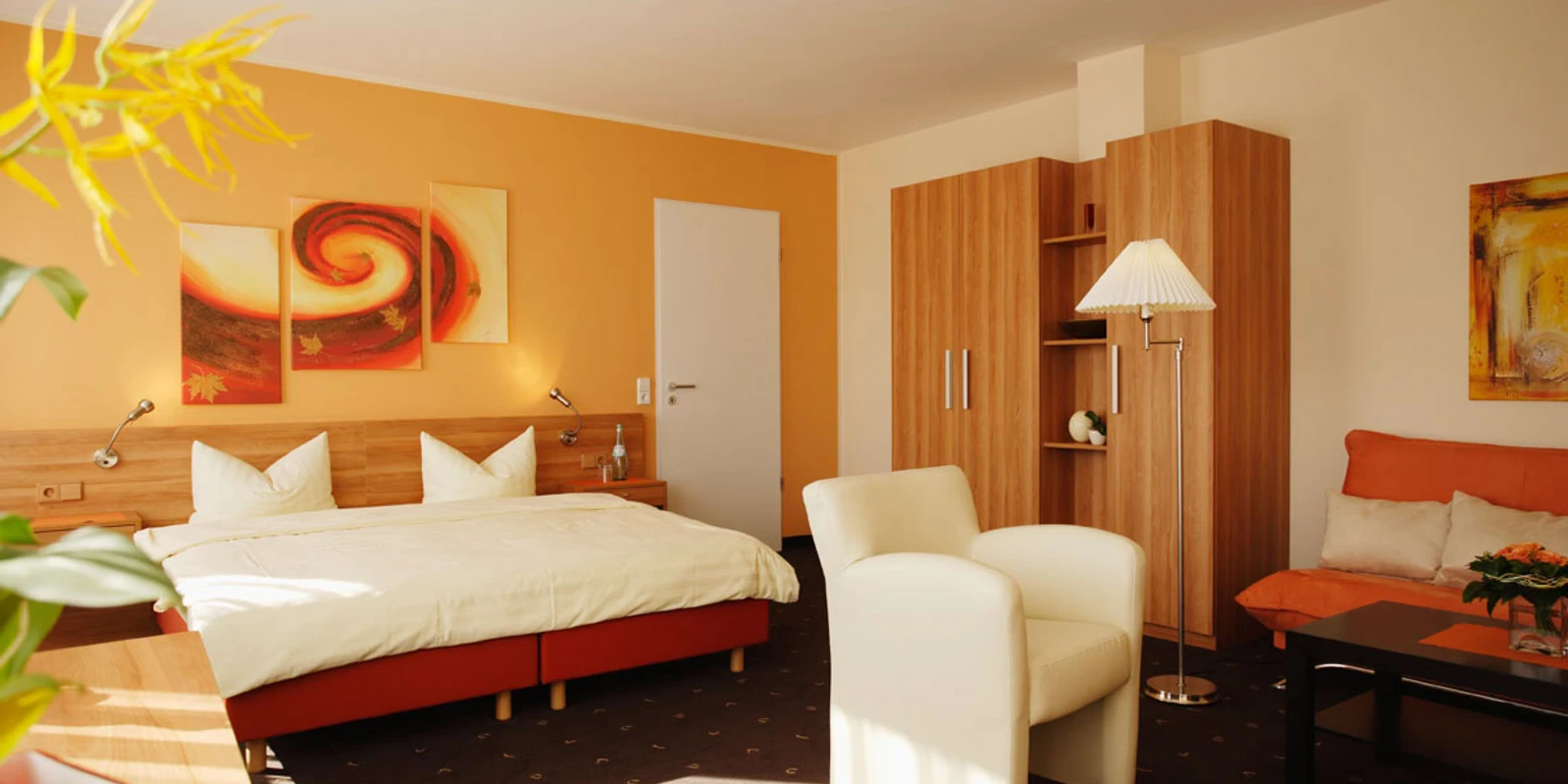 Senne Hotel20071019_0055.jpg Modern eingerichtetes Hotelzimmer mit Doppelbett, Sessel, Sofa, Kleiderschrank und warmen Farbtönen.