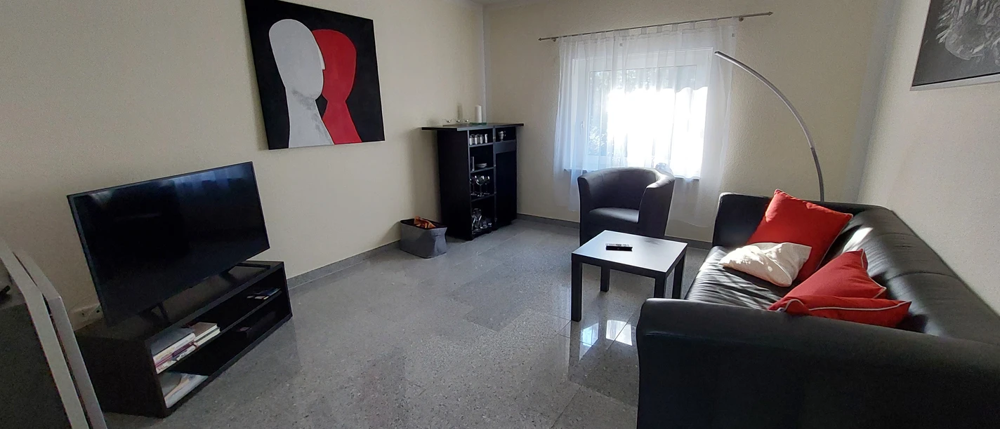 Ferienwohnung_am_Fahrenstau.jpg Helles Wohnzimmer mit Ledersofa, Flachbildfernseher, Couchtisch und modernem Kunstbild an der Wand.