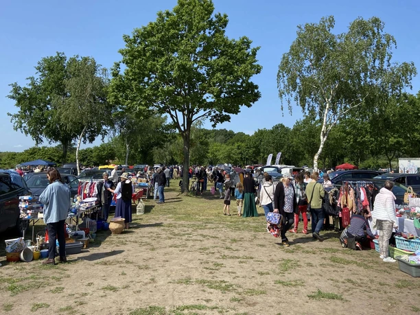 Trödelmarkt in Mardorf, Besucher stöbern zwischen Verkaufsständen im Freien, umgeben von Bäumen.