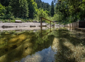 Kneippbecken Farchant Kuhfluchtwasser im Vordergrund mit Stange zum Einhalten, im Hintergrund Bänke