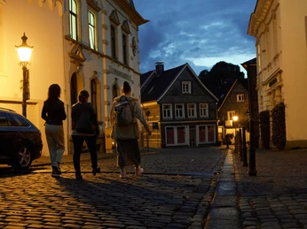 Altstadt Solingen Gräfrath Drei Personen laufen bei Nacht durch die Altstadt Solingen Gräfrath