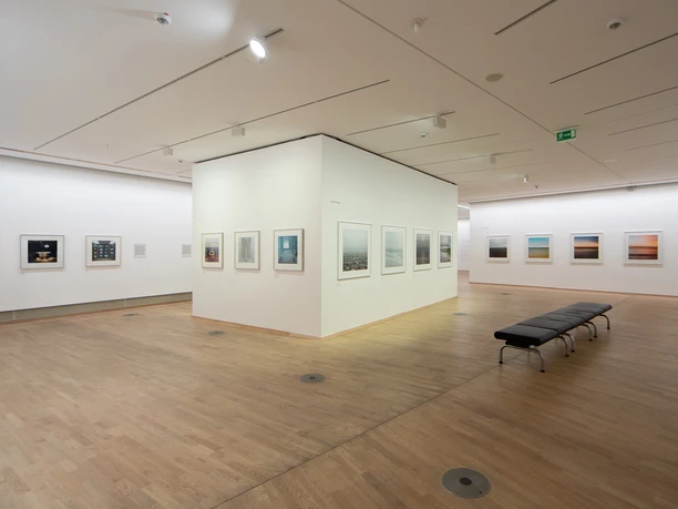 The Photographic Collection/SK Stiftung Kultur A light-flooded exhibition space in a gallery with a wooden floor and framed photographs hanging on the walls.