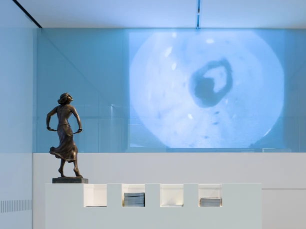 Dance Museum of the German Dance Archive Cologne Bronze bust of a dancing pose in front of a modern wall projection in a contemporary space.