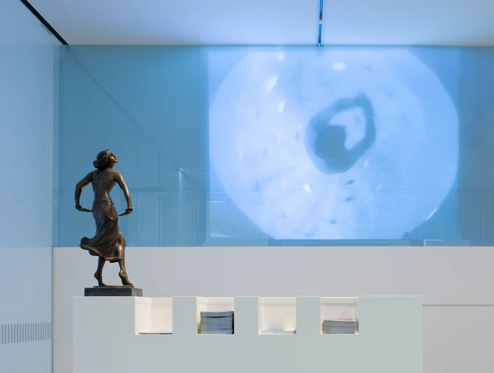 Dance Museum of the German Dance Archive Cologne Bronzebüste einer tänzerischen Pose vor einer modernen Wandprojektion in einem zeitgenössischen Raum.Bronze bust of a dancing pose in front of a modern wall projection in a contemporary space.