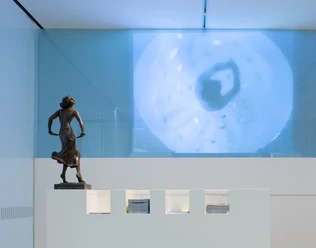 Tanzmuseum des Deutschen Tanzarchivs Köln Bronzebüste einer tänzerischen Pose vor einer modernen Wandprojektion in einem zeitgenössischen Raum.
