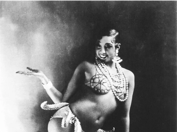 Dance Museum of the German Dance Archive Cologne Josephine Baker poses in a detailed costume of pearls and jewelry, showing graceful gestures and facial expressions in an elegant dance step.