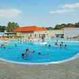 Menschen genießen sommerlichen Badespaß in einem großen Freibad mit verschiedenen Pools.