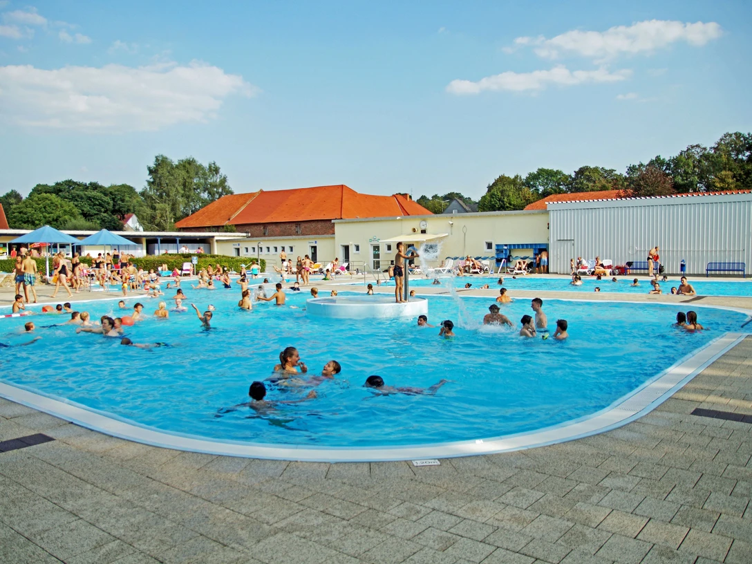Brakel_Sommerbad_Stadt_Brakel_3 Menschen genießen sommerlichen Badespaß in einem großen Freibad mit verschiedenen Pools.