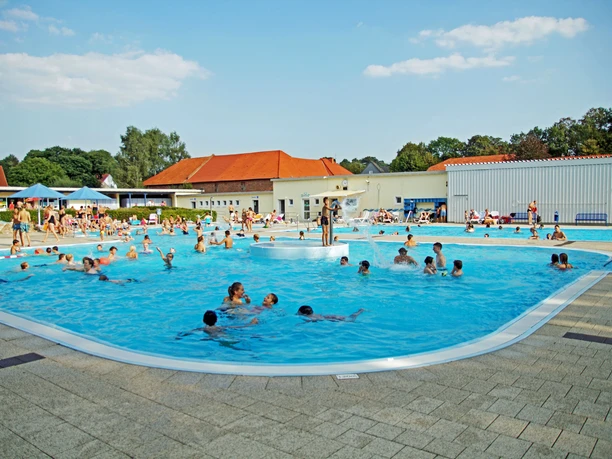 Brakel_Sommerbad_Stadt_Brakel_3 Menschen genießen sommerlichen Badespaß in einem großen Freibad mit verschiedenen Pools.