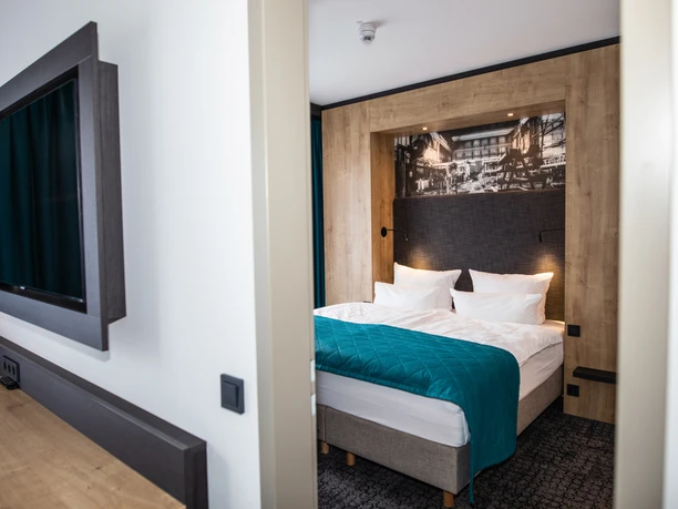 0195.jpg Gemütliches Hotelzimmer mit Doppelbett, modernem Design, Holzwandverkleidung und großem Wandbild.