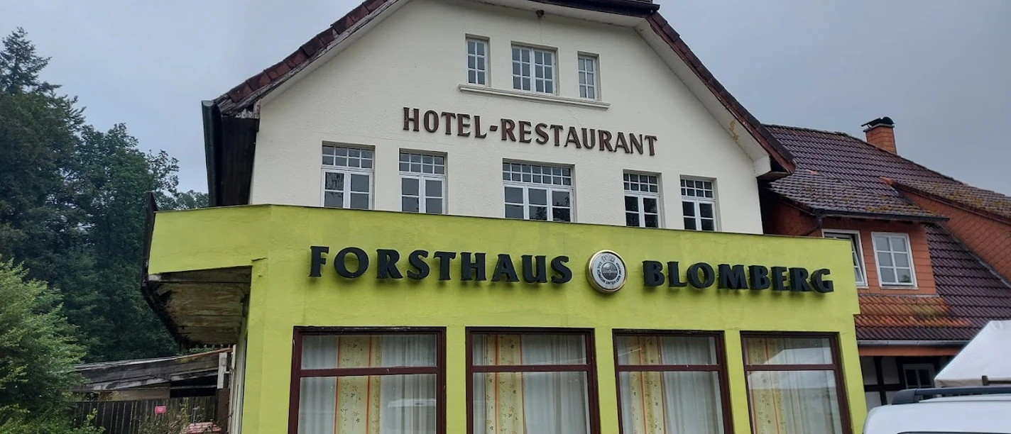 Cafe Forsthaus vor bewölktem Himmel, Teil eines Hotel-Restaurants in einem zweistöckigen Gebäude.