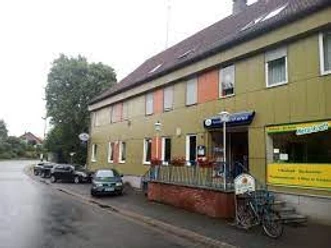 Die Gaststätte Wittelmeyer mit grün-gelblichen Fassaden und orangefarbenen Markisen an den Fenstern.