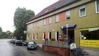 Die Gaststätte Wittelmeyer mit grün-gelblichen Fassaden und orangefarbenen Markisen an den Fenstern.