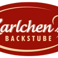 Logo von Karlchens Backstube mit rotem Oval und weißer Schrift, herzförmiges Detail rechts.