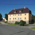 Touristinformation Reinhardtsdorf-Schöna Gelbes zweistöckiges Gebäude mit braunem Dach, umgeben von Bäumen, bei klarem Himmel; ein Schild weist auf die Gemeindeverwaltung hin.Yellow two-story building with a brown roof, surrounded by trees, under a clear sky; a sign indicates the municipal administration.Žlutá dvoupatrová budova s hnědou střechou, obklopená stromy, pod jasnou oblohou; cedule označuje obecní úřad.Żółty dwupiętrowy budynek z brązowym dachem, otoczony drzewami, pod czystym niebem; znak wskazuje administrację miejską.Geel gebouw van twee verdiepingen met een bruin dak, omringd door bomen, onder een heldere hemel; een bord geeft de gemeentelijke administratie aan.Edificio giallo a due piani con tetto marrone, circondato da alberi, sotto un cielo sereno; un cartello indica l'amministrazione comunale.