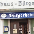 speisekartenweb.jpg Eingang des Restaurants Bürgerheim mit blauem Schild und Herforder-Logo, Holztür und Fenster.