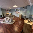 Ausstellungsraum mit historischen Werkzeugen und Infotafeln auf Holzboden, Fokus auf großen Holzwagen.