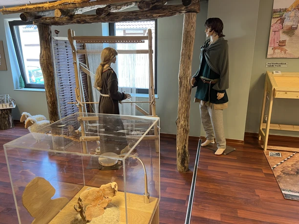 Das Bild zeigt eine Ausstellung mit lebensgroßen Figuren in traditioneller mittelalterlicher Kleidung.