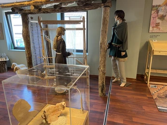 Altsachsenausstellung Liebenau Das Bild zeigt eine Ausstellung mit lebensgroßen Figuren in traditioneller mittelalterlicher Kleidung.