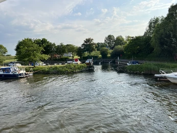 Sportboothafen Hoya Sportboothafen Hoya mit Sportbooten, ruhiger Fluss, grüner Umgebung und bewölktem Himmel.