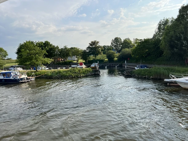 Sportboothafen Hoya Sportboothafen Hoya mit Sportbooten, ruhiger Fluss, grüner Umgebung und bewölktem Himmel.